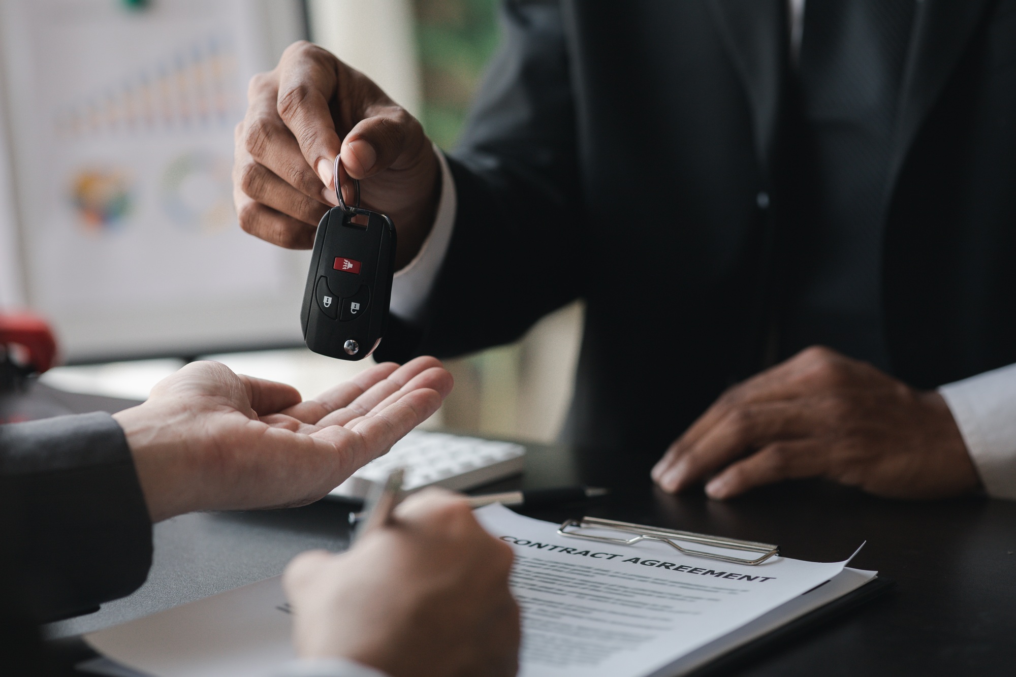 A car rental company employee pointed out the renter to sign the rental agreement after discussing t